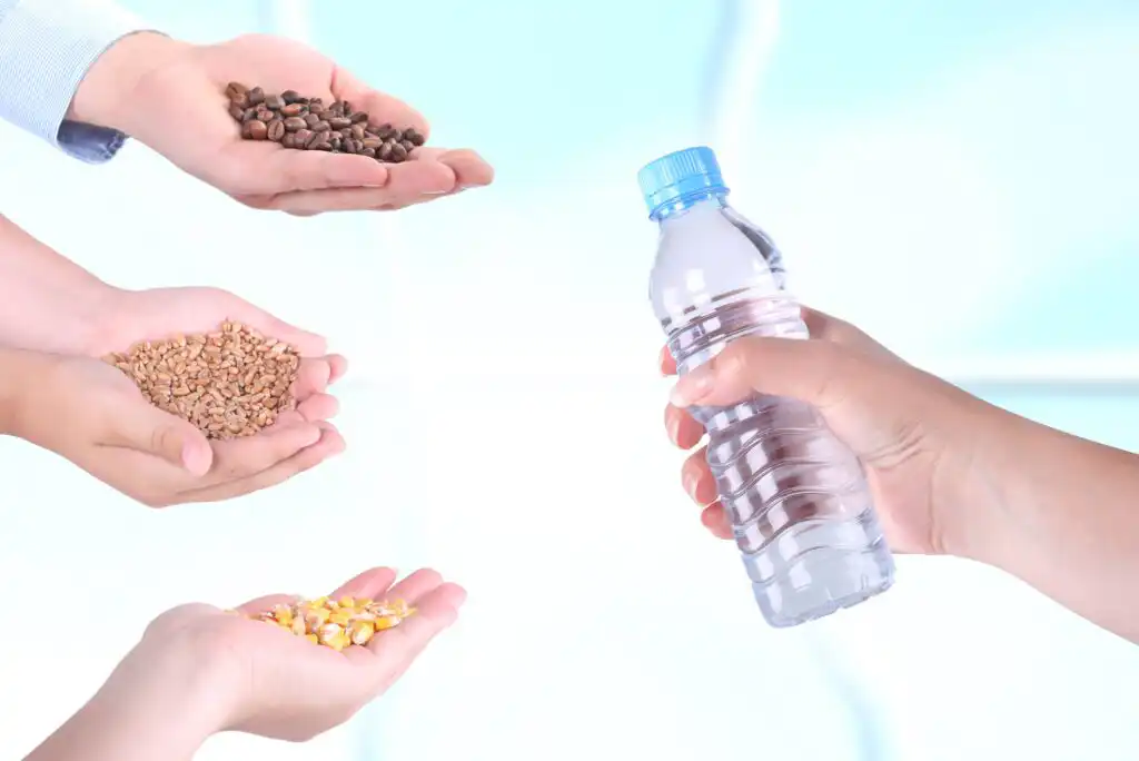 Three hands holding coffee beans, grains, and corn kernels face a fourth hand holding a clear plastic water bottle, against a light blue and white background.