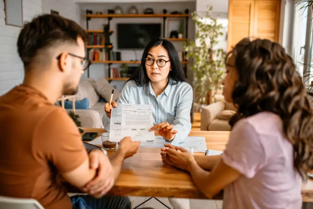 A woman holding a paper with a man and a woman sitting at a table.