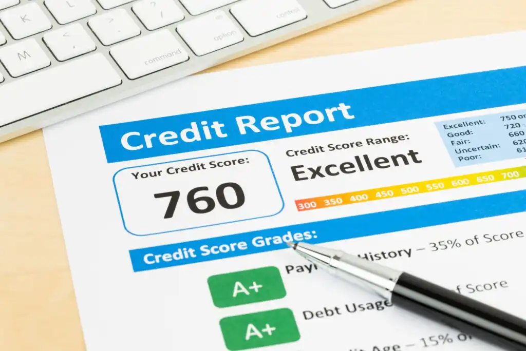 A credit report showing a credit score of 760 labeled as “Excellent.” A pen lies on the paper, and a keyboard is partially visible in the background. The report also lists credit score grades.