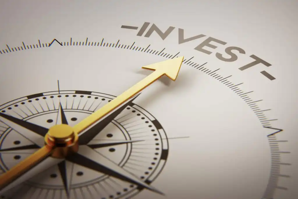 A gold compass needle points toward the word INVEST on a detailed compass face, symbolizing direction and guidance in financial decision-making.
