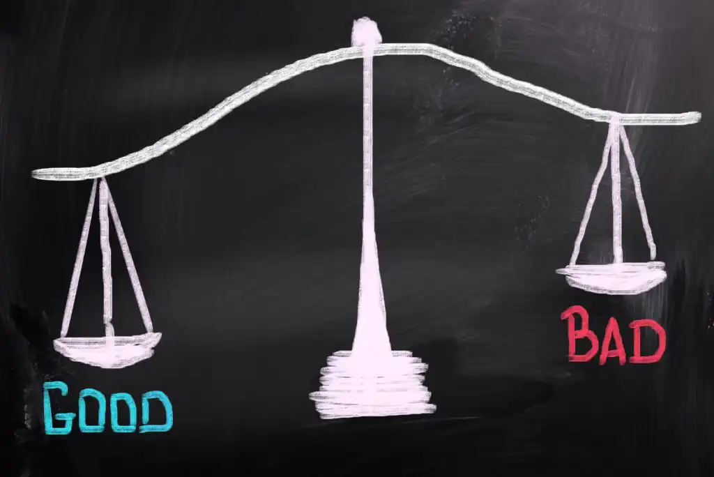 A chalk drawing on a blackboard shows a tilted balance scale, with GOOD in blue on the heavier left side and BAD in red on the lighter right side. The scale favors GOOD.