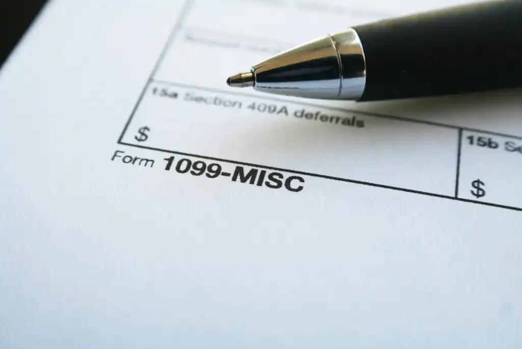 A close-up of a 1099-MISC tax form with a black pen resting on top, highlighting the forms title and part of a section for entering monetary amounts.