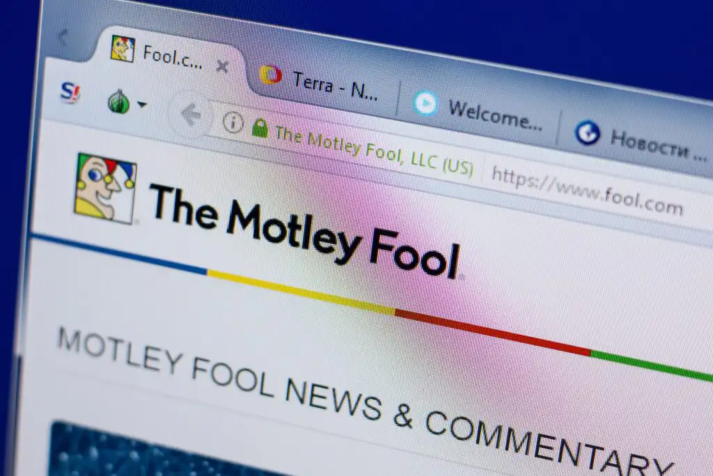 A computer screen displays The Motley Fool website with its logo and partial website address visible in the browser tab. Several other browser tabs are open above the site’s headline.