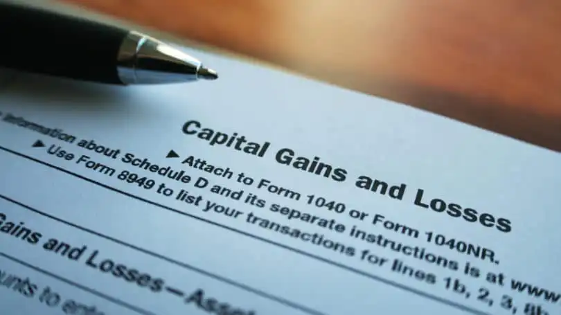 A close-up of a tax form titled Capital Gains and Losses with a pen resting on top, focusing on the section about attaching to Form 1040 or 1040NR.