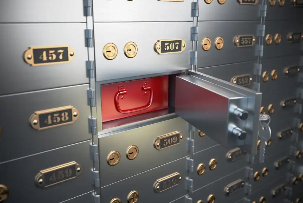 A row of metal safety deposit boxes with gold number plates; one box labeled 507 is open, revealing a red briefcase inside.