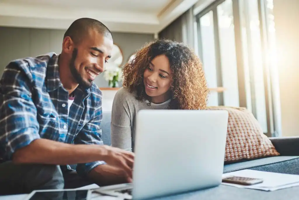 A man and woman looking at a laptop.