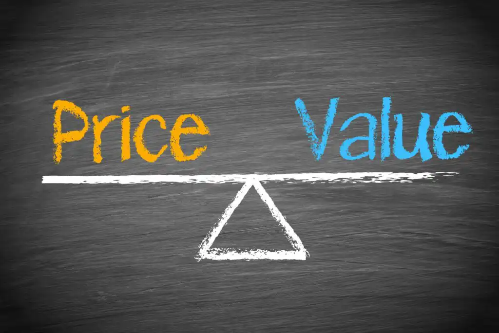 A chalk drawing on a blackboard shows the words Price (in orange) and Value (in blue) balanced on a white seesaw, symbolizing the relationship between price and value.